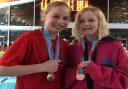 Huntingdon Piranha swimmers Felicity Fitzgerald (L) and Taylor McCarthy (R) with their medals from the County Championships.