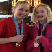 Huntingdon Piranha swimmers Felicity Fitzgerald (L) and Taylor McCarthy (R) with their medals from the County Championships.