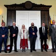 Cllr Karl Webb (Armed Forces Champion), Cllr Steve McAdam, Cllr Audrey McAdam (Deputy Mayor), Cllr David Landon Cole (Mayor of Huntingdon), Gordon Peacock (Royal British Legion) and Harry Raby (Royal British Legion) beneath the Roll of Honour.